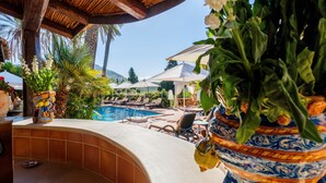 Zona junto a la piscina con sillas de descanso, una piscina y un florero decorativo.