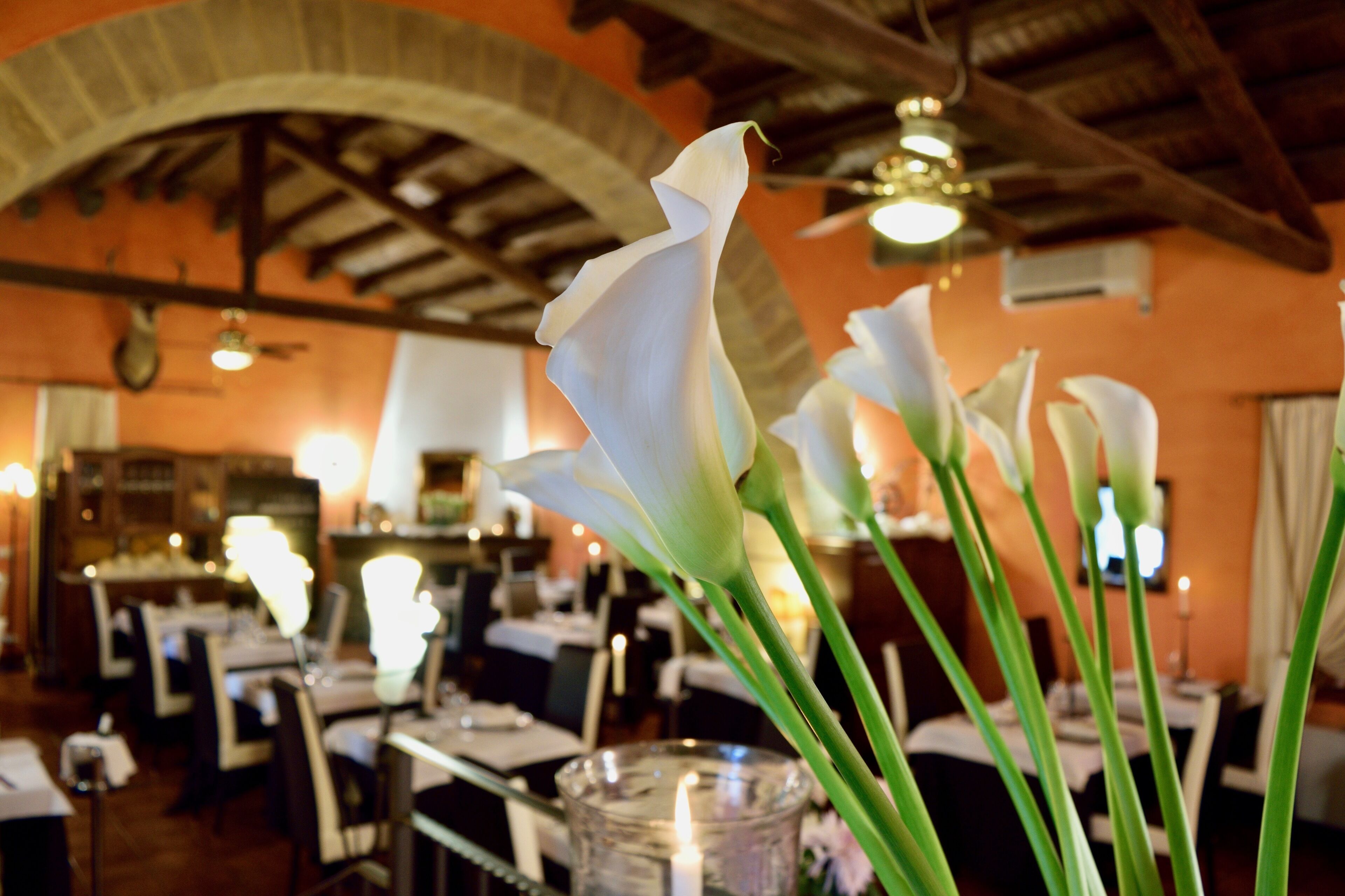 Ein Restaurantinneres mit Tischen, Stühlen und einer Kerzenarrangements in der Mitte.