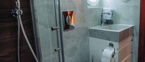 Une salle de bain moderne avec une douche à parois de verre, des toilettes blanches, un lavabo en marbre et un distributeur de serviettes.
