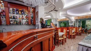 Een barruimte met houten toonbanken, diverse flessen drank en een zithoek met houten stoelen en tafels.
