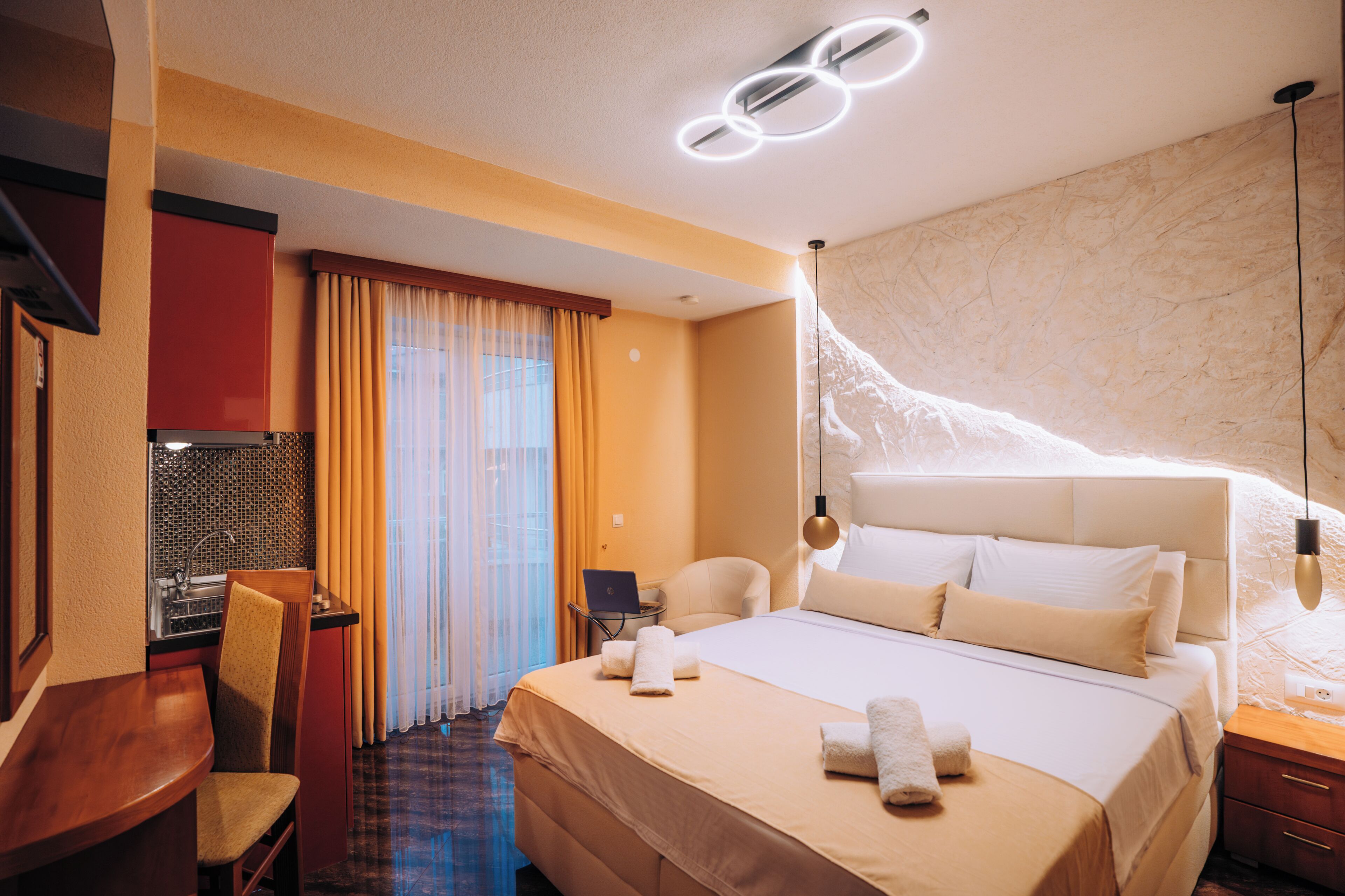 Una habitación de hotel con cama, escritorio, silla y ordenador portátil.