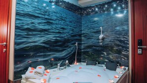 Een kamer met een groot bad, een muurschildering van een meer en een plafond met inbouwverlichting.