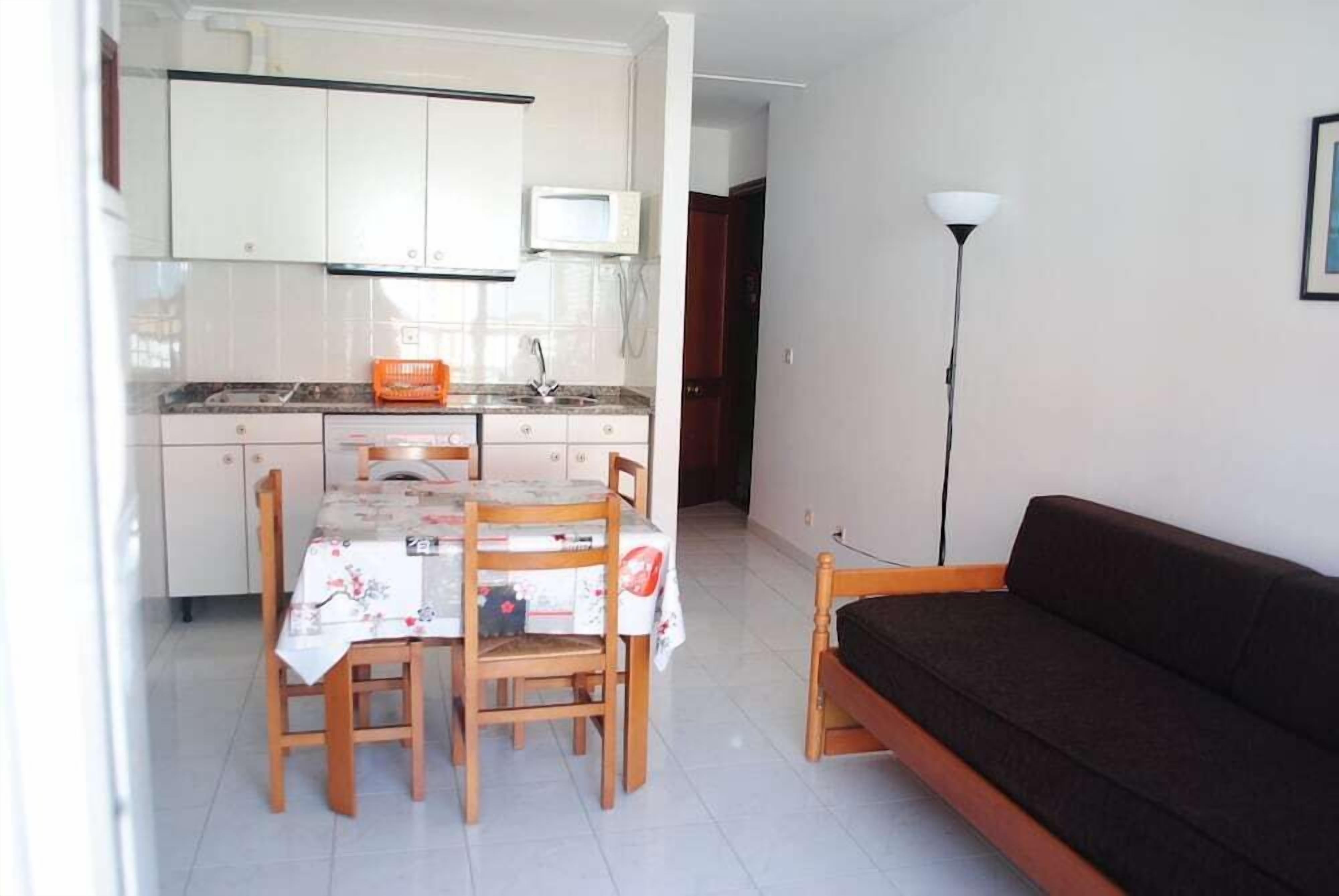 A compact living space with a kitchenette, a dining area with a table and chairs, and a sofa.