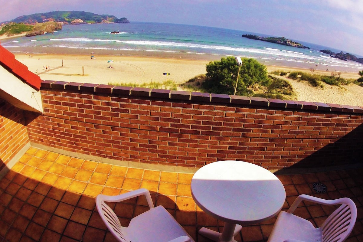 A patio with a table and chairs overlooking a beach.