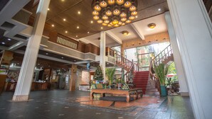 Un vestíbulo amplio con una escalera central, una zona de recepción y un árbol de Navidad.