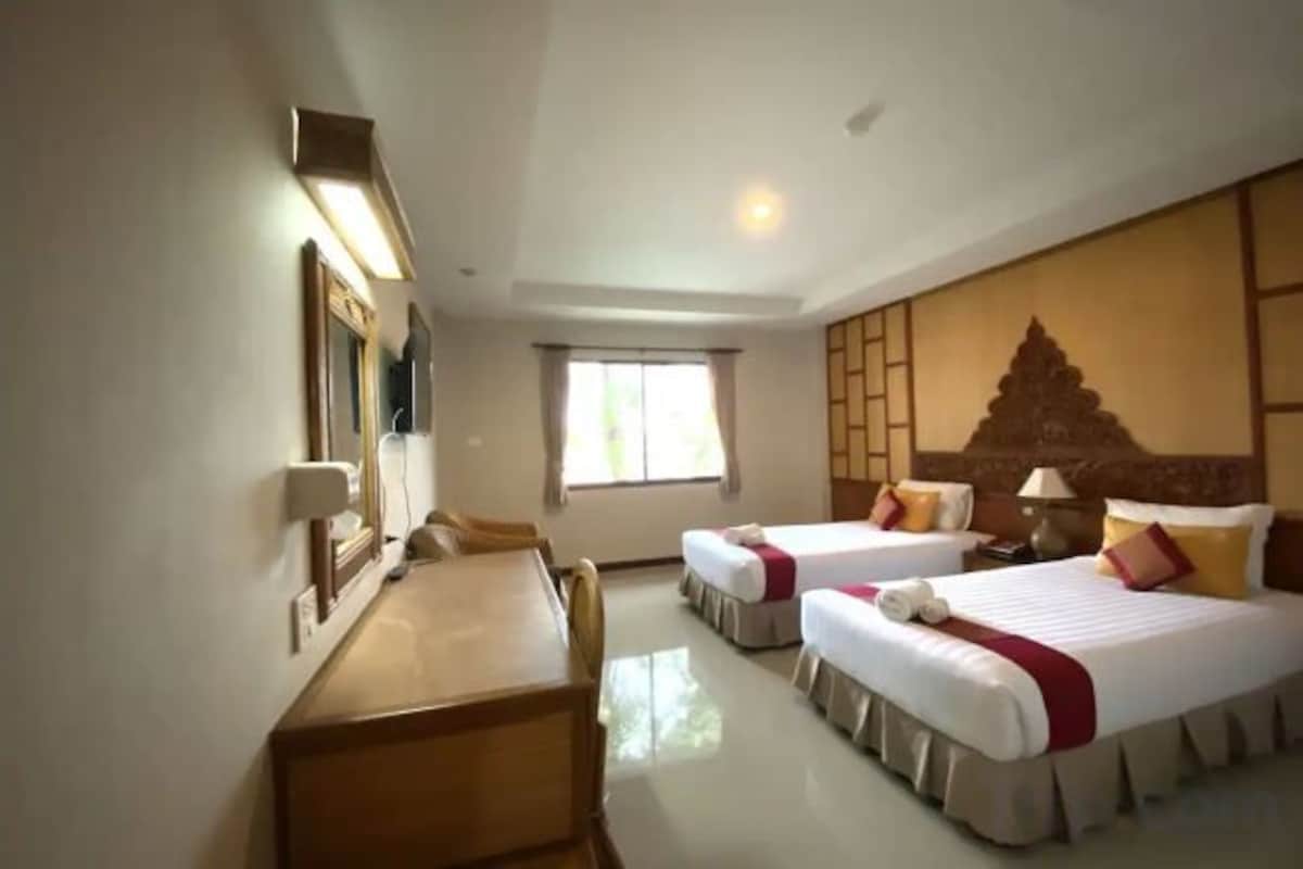 Habitación de hotel con dos camas, un escritorio y un ventanal grande.