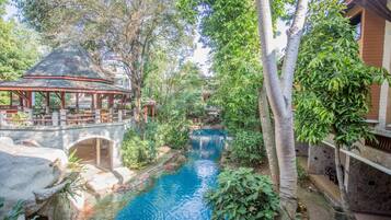 Relax by the serene pool surrounded by lush greenery and a shaded gazebo.