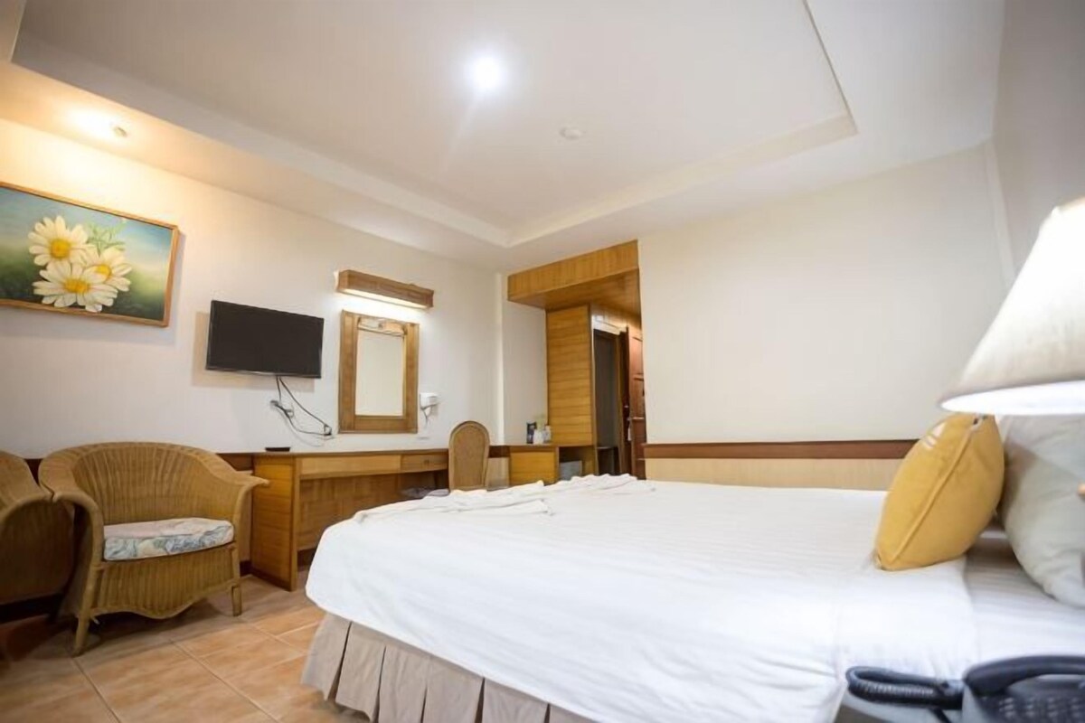 A hotel room with a bed, a desk, a chair, a television, and a painting.