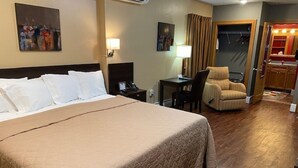Ein Hotelzimmer mit einem großen Bett, einem Schreibtisch, einem Sessel und einem durch eine offene Tür einsehbaren Badezimmer.