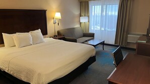 A hotel room with a large bed, a desk, a chair, and a sofa. - Days Inn by Wyndham Duluth Lakewalk (Duluth)