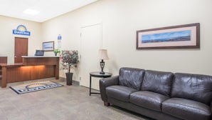 A Days Inn reception area with a reception desk, a leather couch, a framed landscape picture, and a small table with a lamp. - Days Inn by Wyndham Duluth Lakewalk (Duluth)
