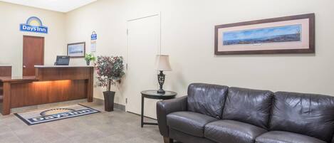 A Days Inn reception area with a reception desk, a leather couch, a framed landscape picture, and a small table with a lamp.