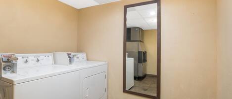A hotel bathroom with a large mirror, a washing machine, and a dryer.