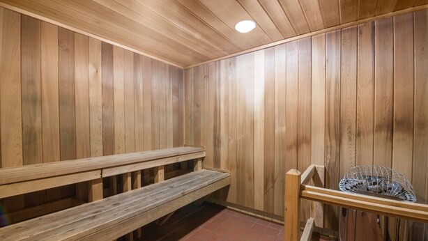 A wooden sauna with benches and a metal basket. - Days Inn by Wyndham Duluth Lakewalk (Duluth)