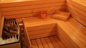 A sauna with wooden benches and a metal container of wood shavings.