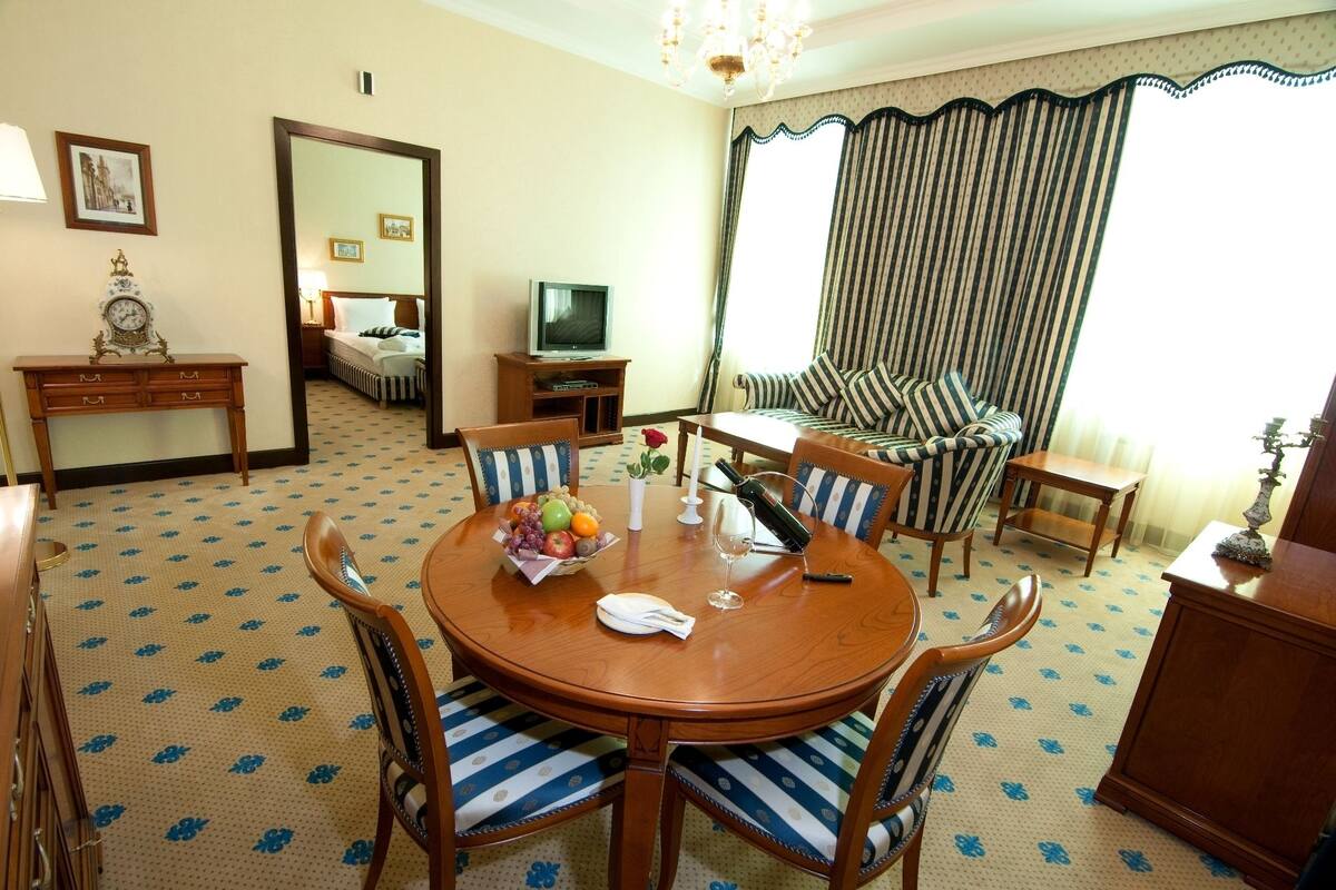 A hotel room with a round dining table, striped sofa, and a television.