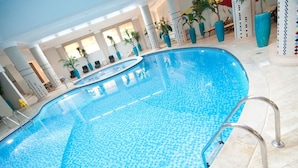 An indoor swimming pool with clear blue water, surrounded by lounge chairs and potted plants. - Grand Hotel Tien Shan (Almaty)