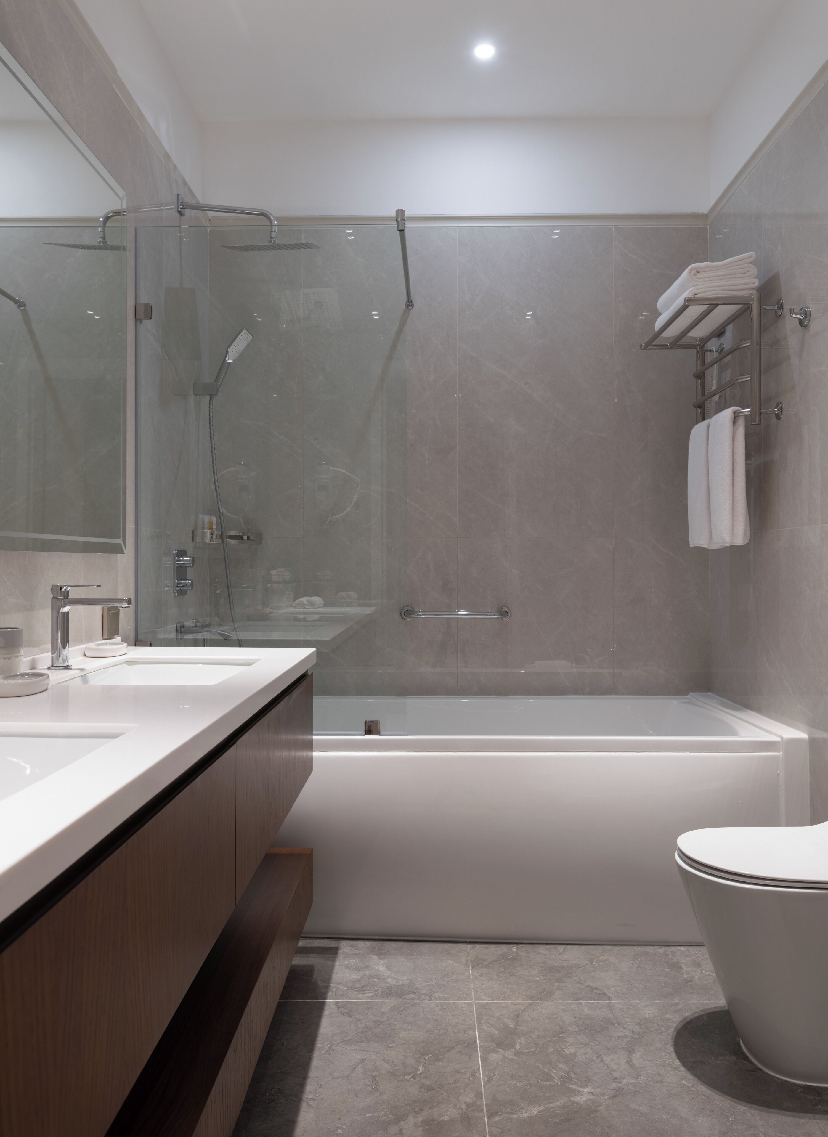 A modern bathroom with a glass-enclosed shower, a bathtub, and a toilet.