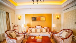 A room with a sofa set, two armchairs, a coffee table, and wall-mounted lamps.