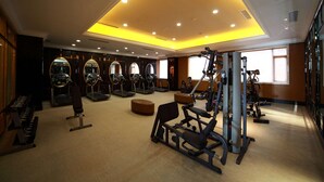A gym with exercise equipment, mirrors, and a piano.