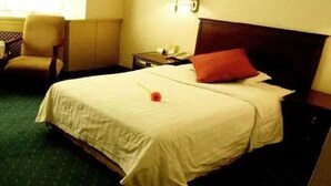 Una habitación de hotel con una cama grande, una silla, una mesita de noche y una lámpara.