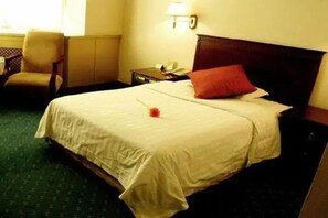 A hotel room with a large bed, a chair, a nightstand, and a lamp. - Howard Johnson by Domando Plaza Wulanchabu (Ulaan Chab)