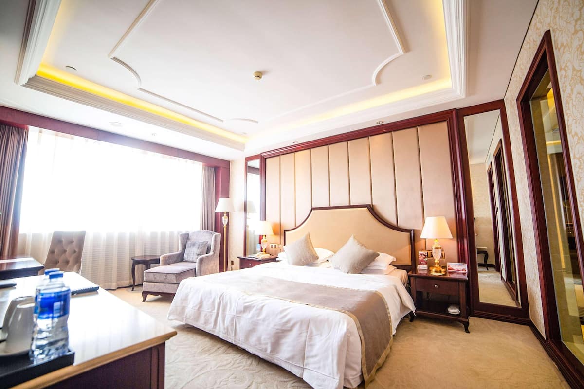 Habitación de hotel con una cama grande, un escritorio con silla, una mesita y un espejo.