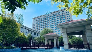 A hotel with a large building, a swimming pool, and a gazebo.