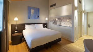 A modern hotel room with a large bed, two bedside tables with lamps, a wall-mounted artwork, and a sliding door closet. - Boiardo Hotel (Scandiano)