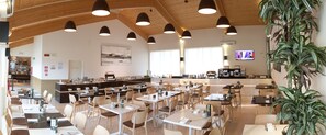 Un restaurante espacioso con techos altos, iluminación colgante y diversas opciones de asientos.