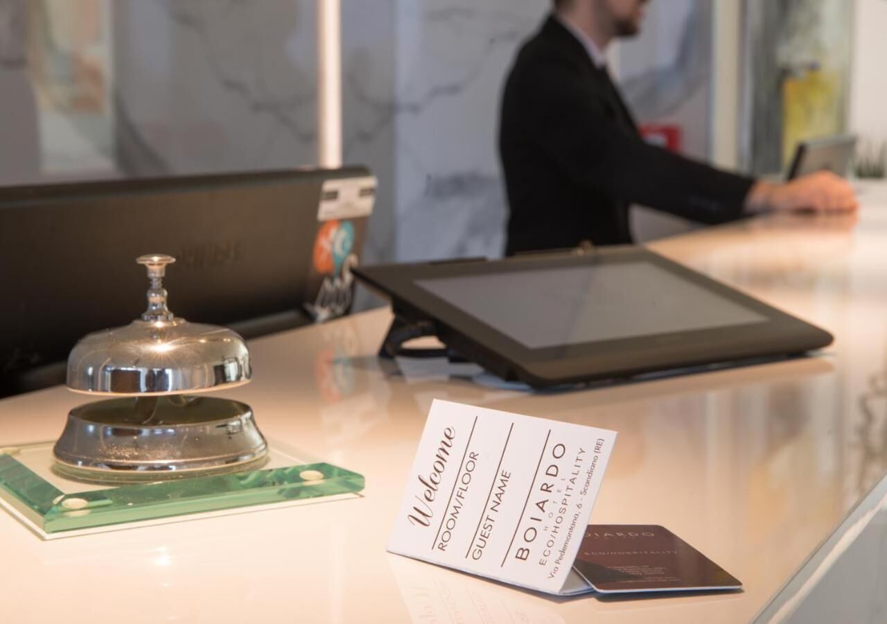 Un comptoir d’accueil d’hôtel avec un présentoir à cartes de visite, une tablette et une clochette.
