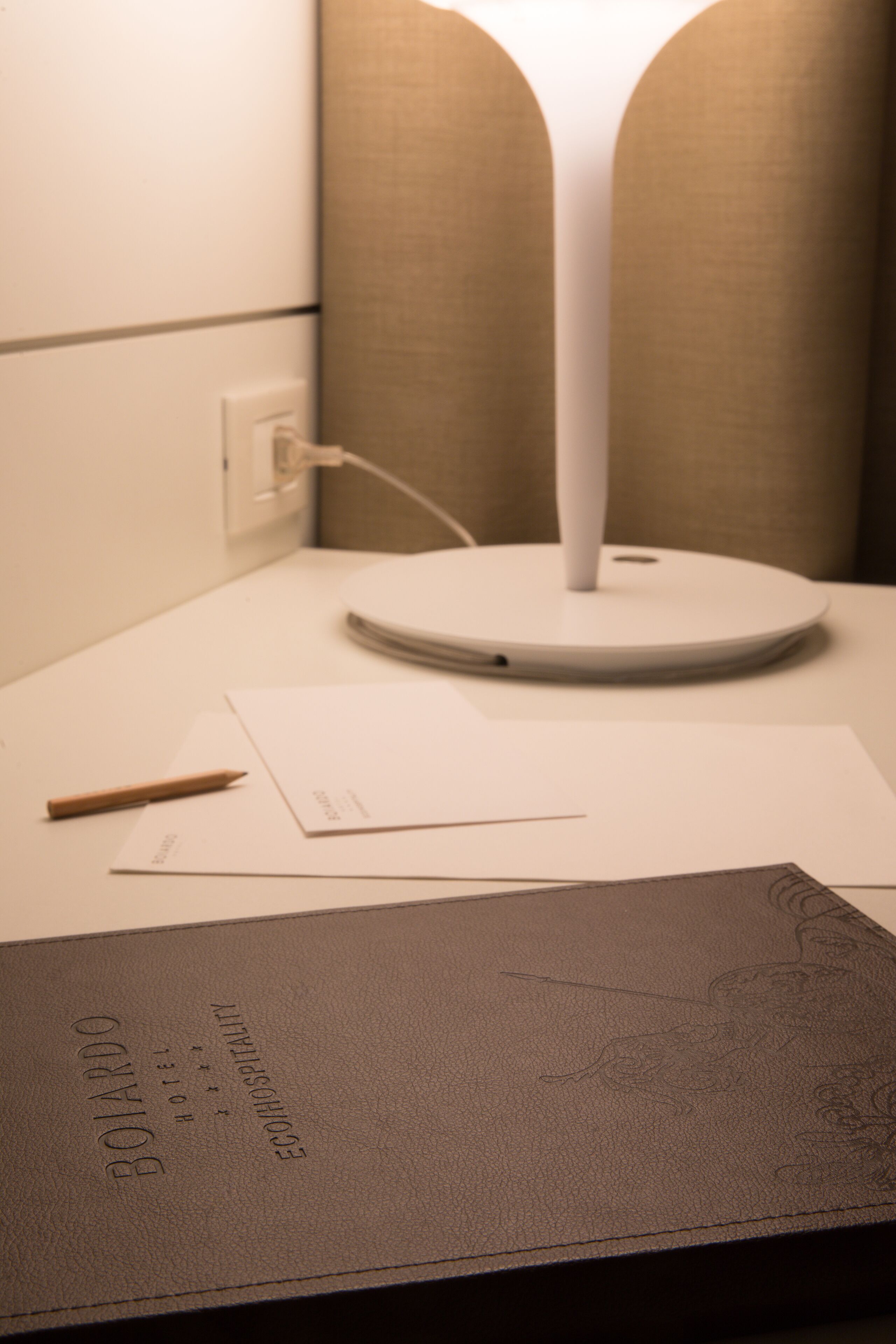 A desk with a lamp, a notebook, and a pen.