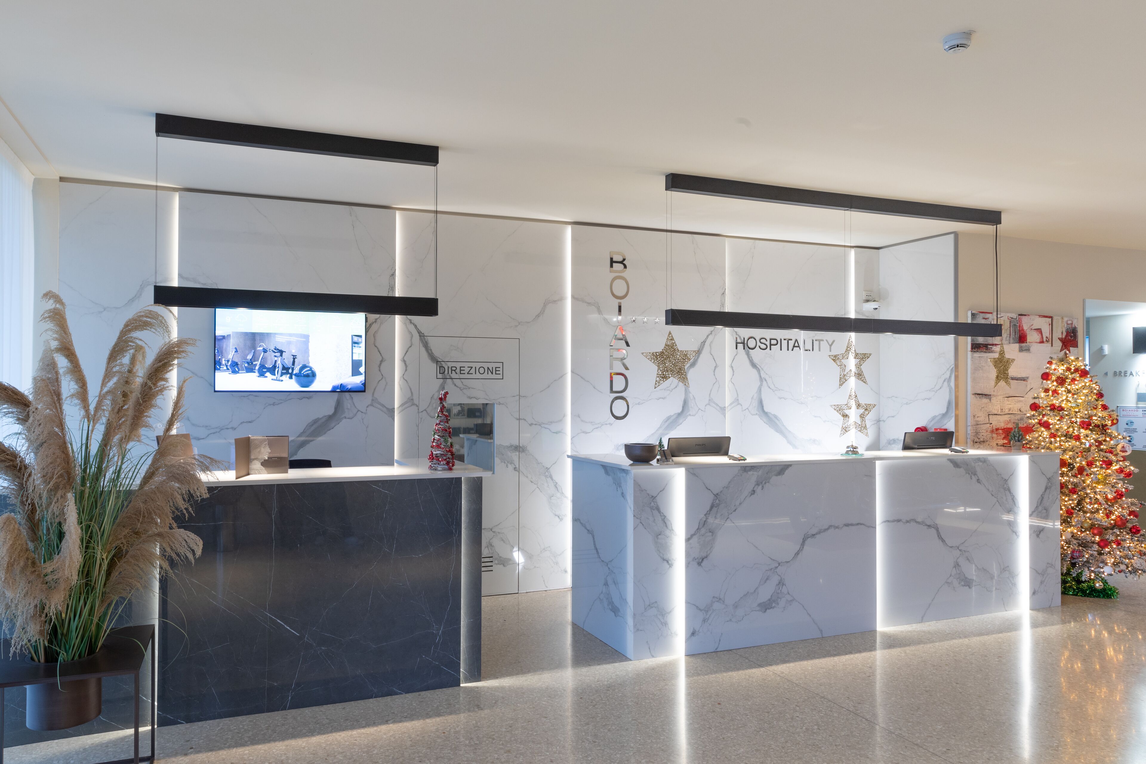 A modern reception area with marble counters, a Christmas tree, and a television screen.
