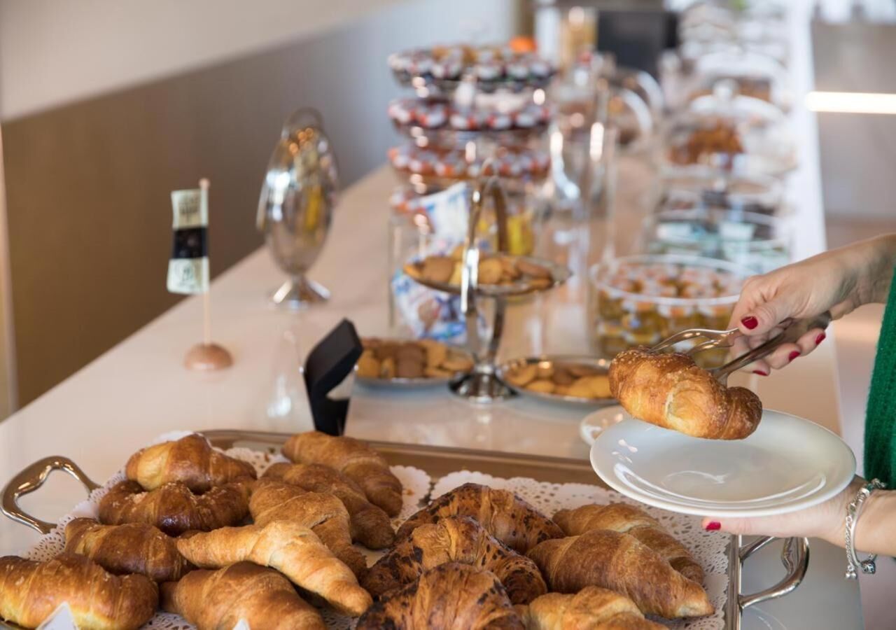 Una mesa de buffet con diversos pasteles y una persona sirviendo un croissant.