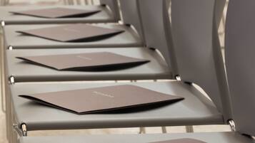 Rows of modern chairs with brown folders on them, arranged in a conference room setting.