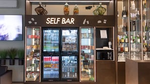 A self-service bar with refrigerated beverage dispensers, shelves of snacks, and a selection of bottled beverages. - Boiardo Hotel (Scandiano)