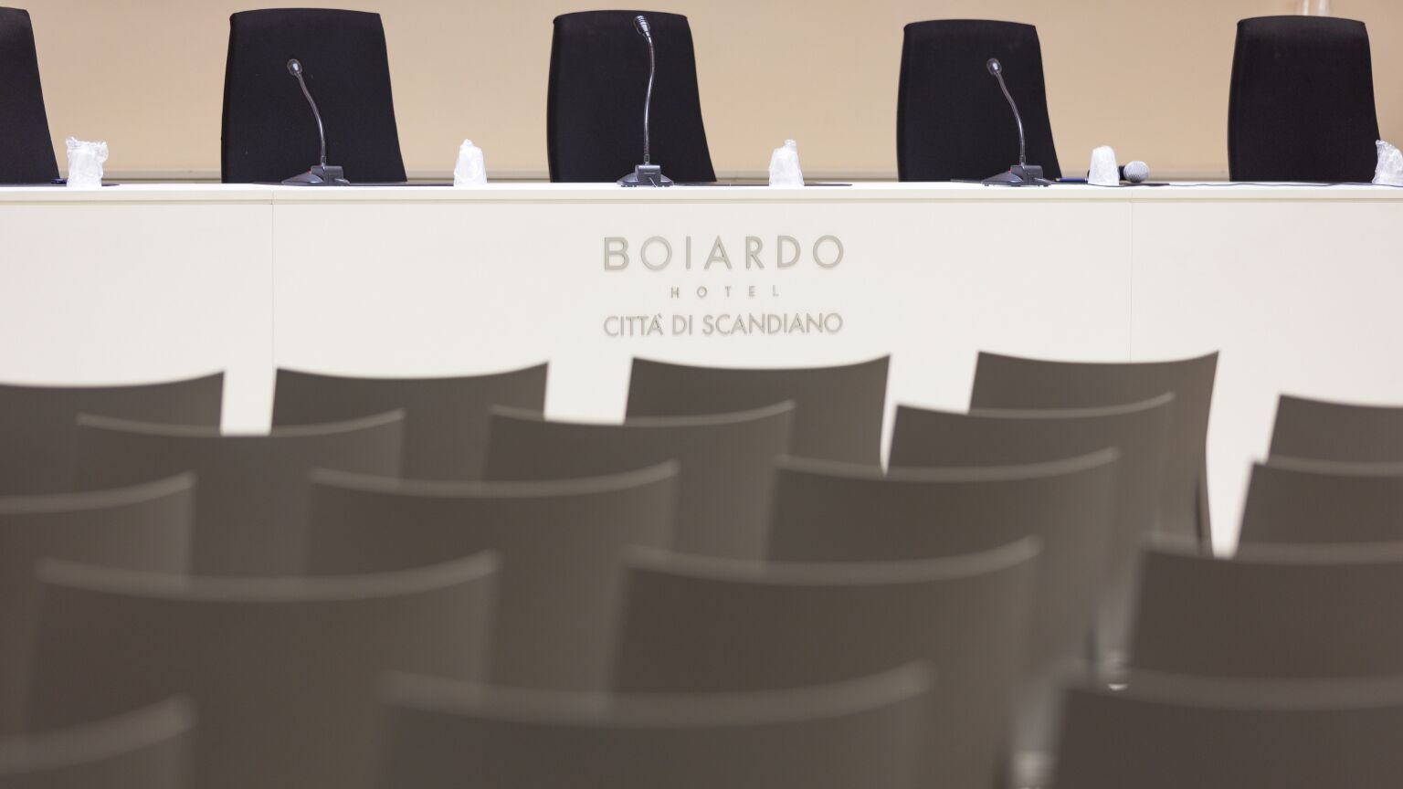 A conference table with microphones and nameplates at the BOIARDO HOTEL in CITTÀ DI SCANDANO.