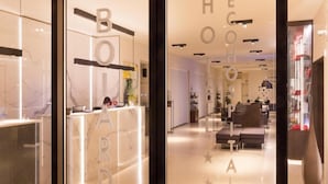 A modern hotel lobby with a reception desk, seating area, and a visible staircase. - Boiardo Hotel (Scandiano)