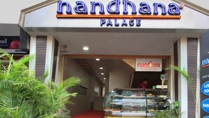 The entrance to a hotel named 'nandhana Palace' with a glass display case in front. - La Sara Vista (Bengaluru)