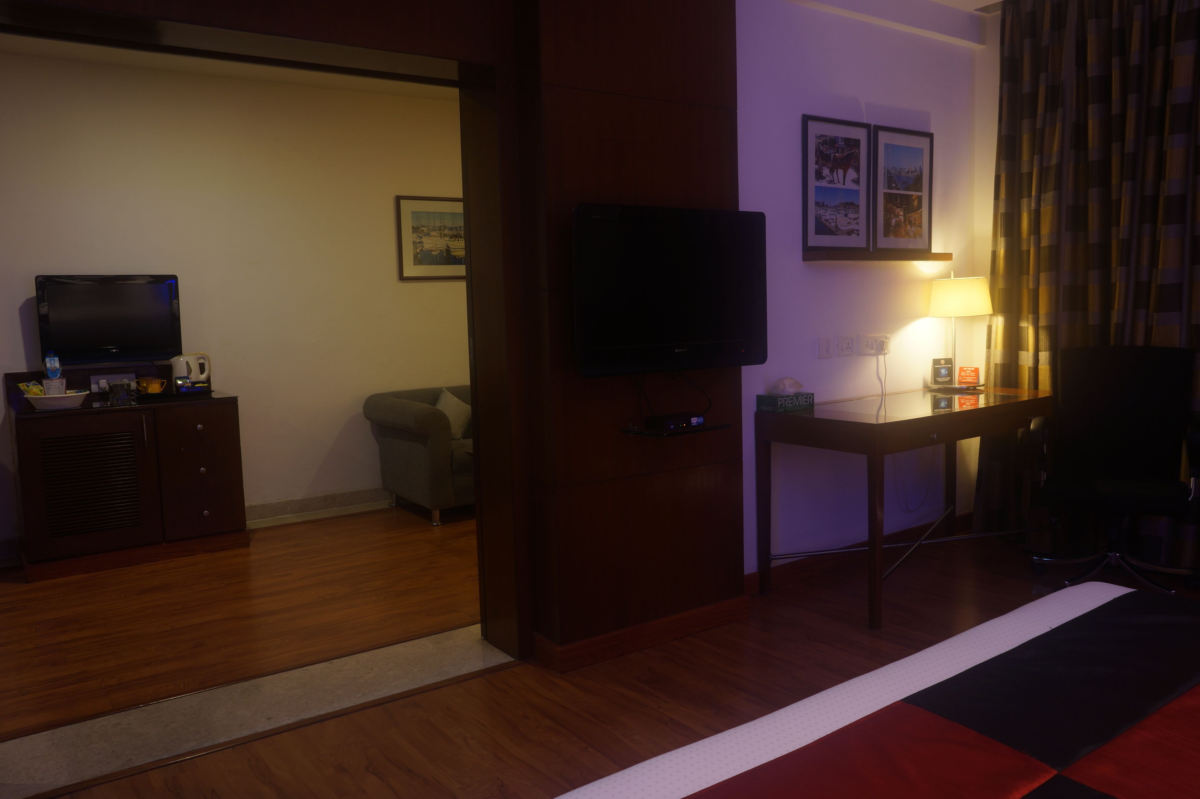 Ett hotellrum med en tv, ett skrivbord med en lampa, en soffa och en säng.