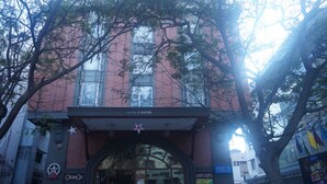 A hotel with a red brick facade, large windows, and a star logo above the entrance. - SFO Hotel and Suites (Bengaluru)