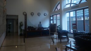 A hotel lobby with a reception desk, a man standing behind it, and a sign reading "BAYSHORE". - SFO Hotel and Suites (Bengaluru)