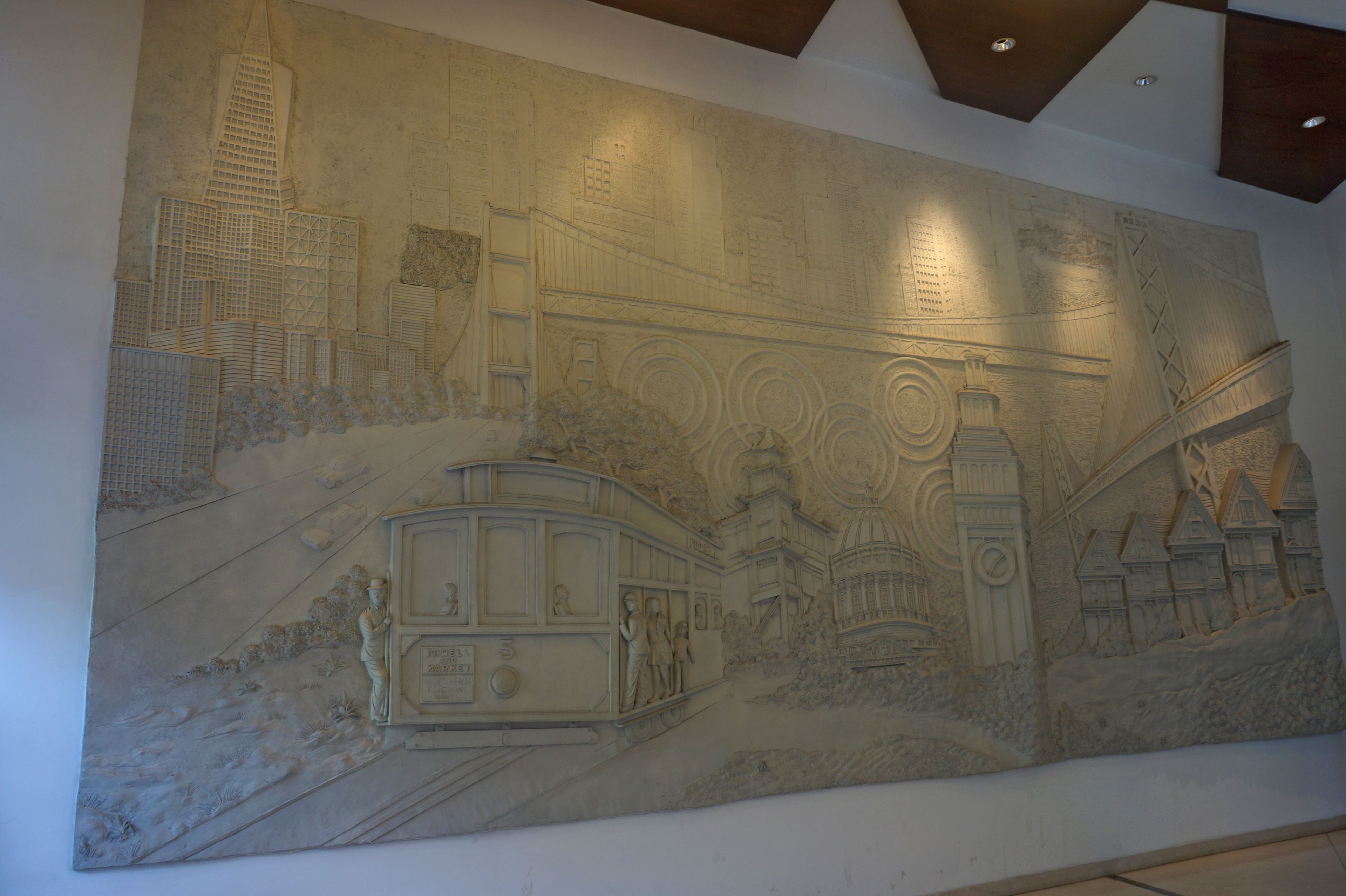 A large, detailed mural depicting a cityscape with buildings, a tram, and people.