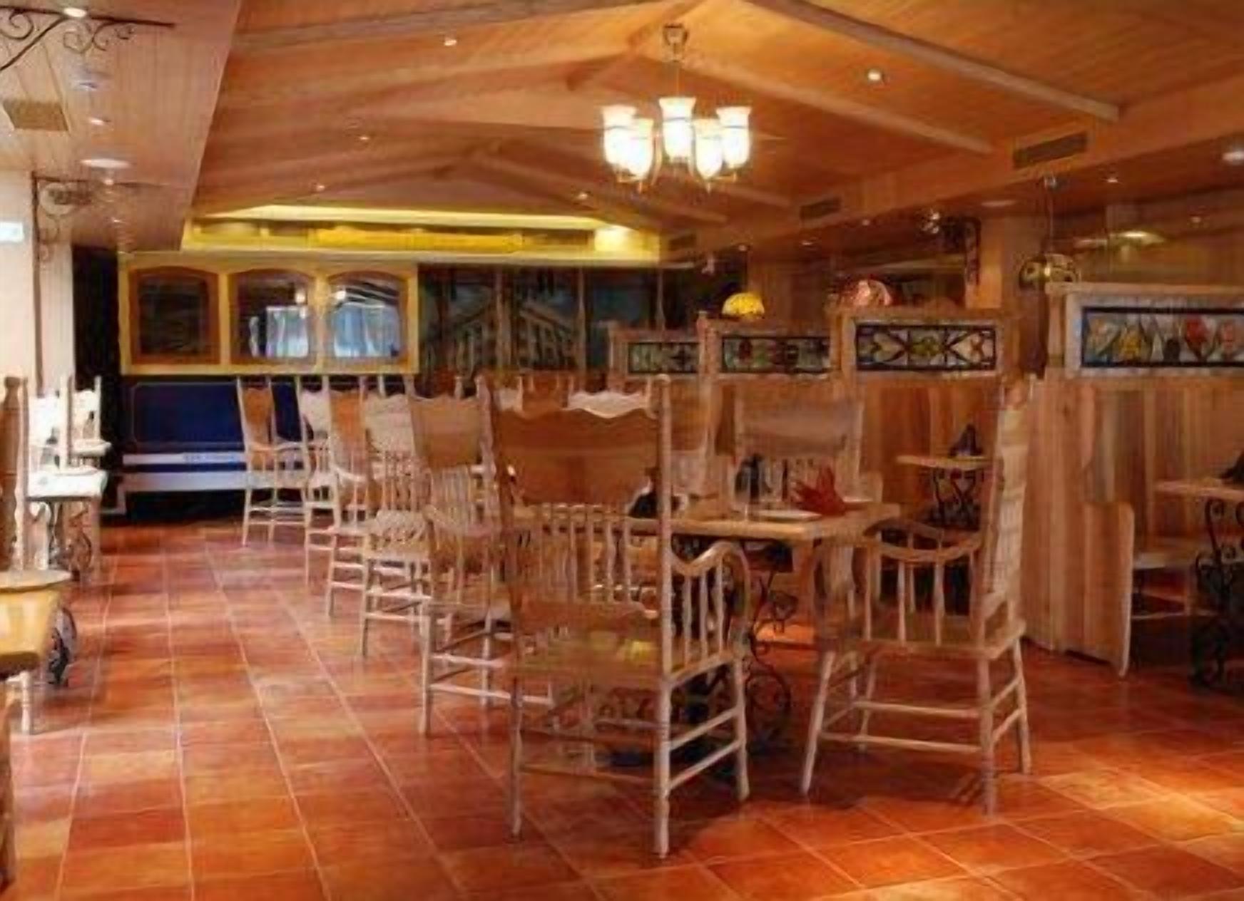 A restaurant interior with wooden chairs and tables, tiled flooring, and decorative elements on the walls.