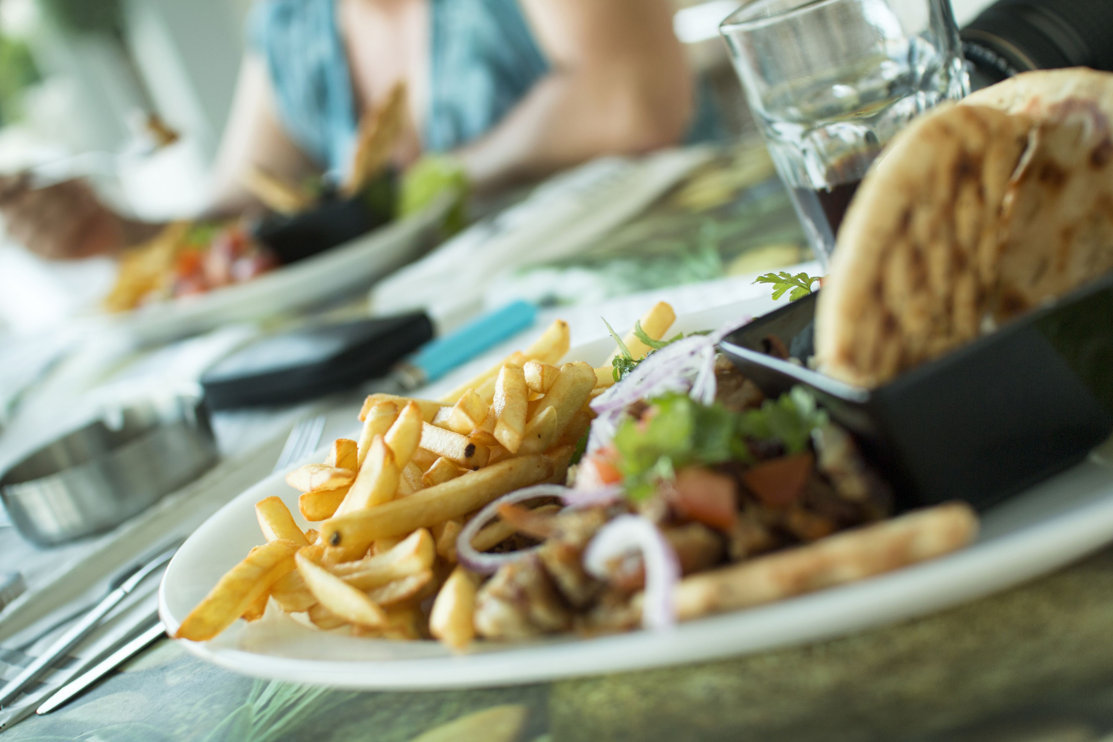 Un plato con papas fritas, un pan plano y un tenedor sobre una mesa.