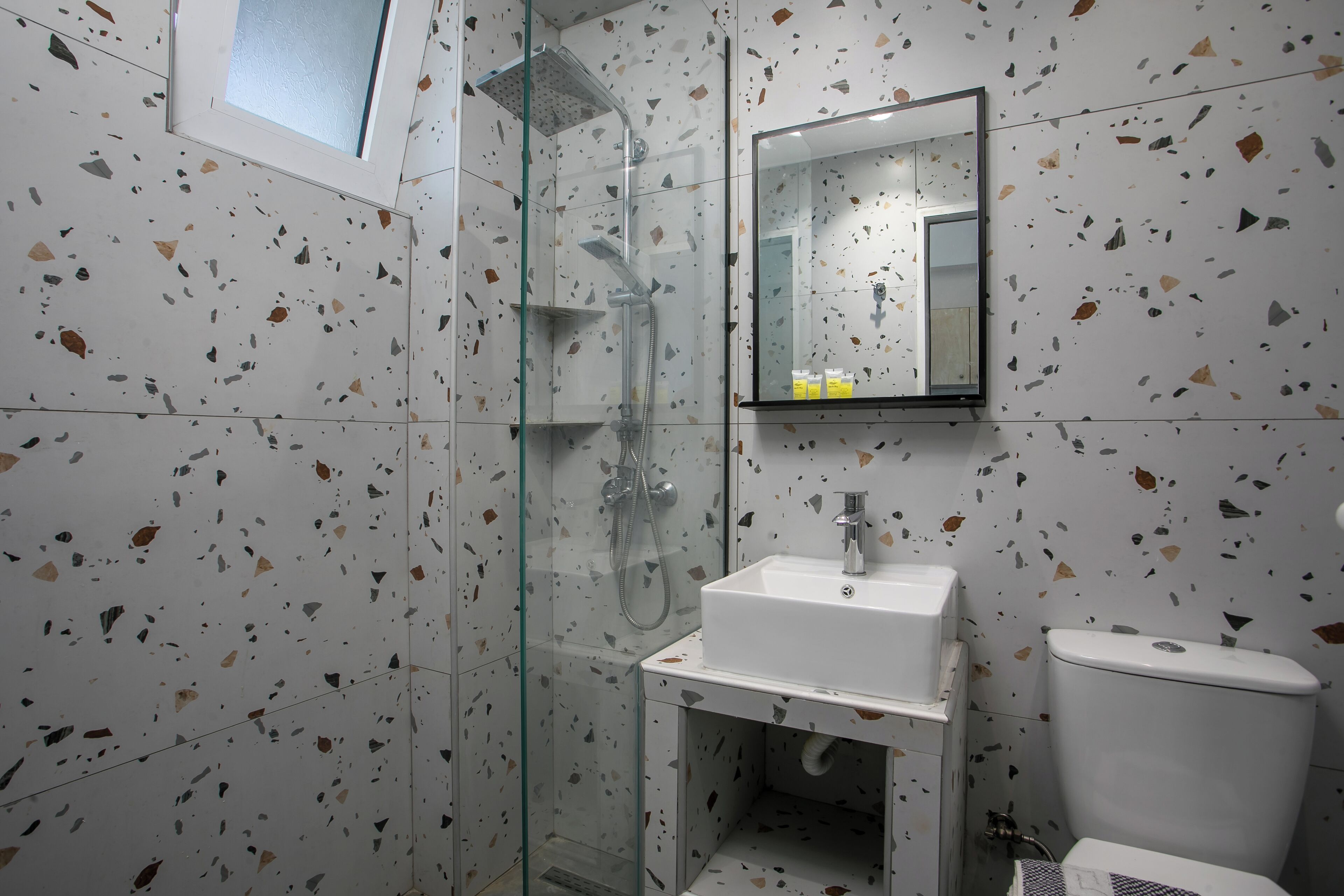 A bathroom with a glass shower enclosure, a white sink, and a toilet.