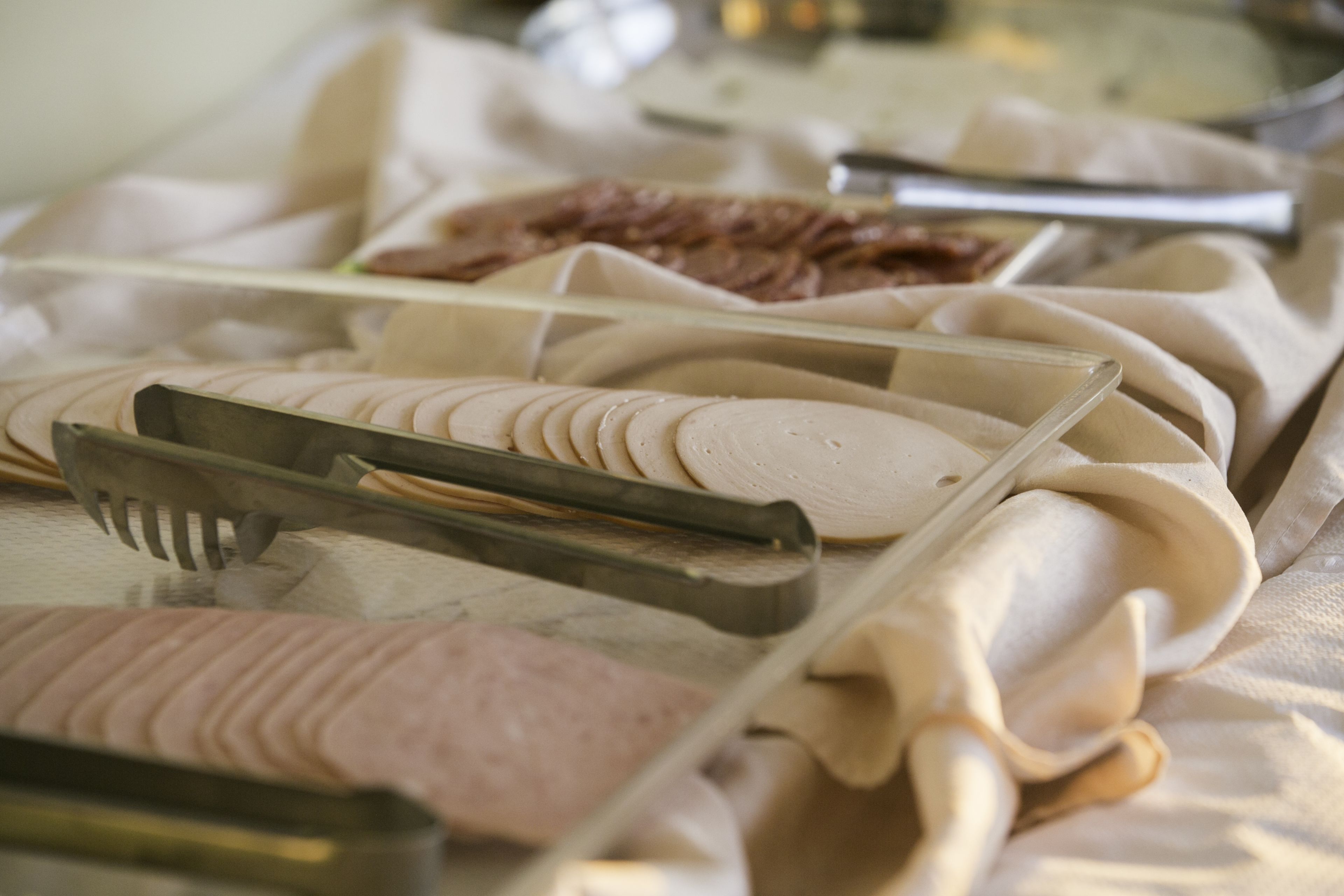 A buffet with various food items, including sliced meats and desserts, arranged on a table with serving utensils.