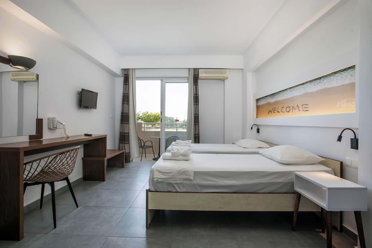 A modern hotel room with a bed, desk, chair, and a "WELCOME" sign.