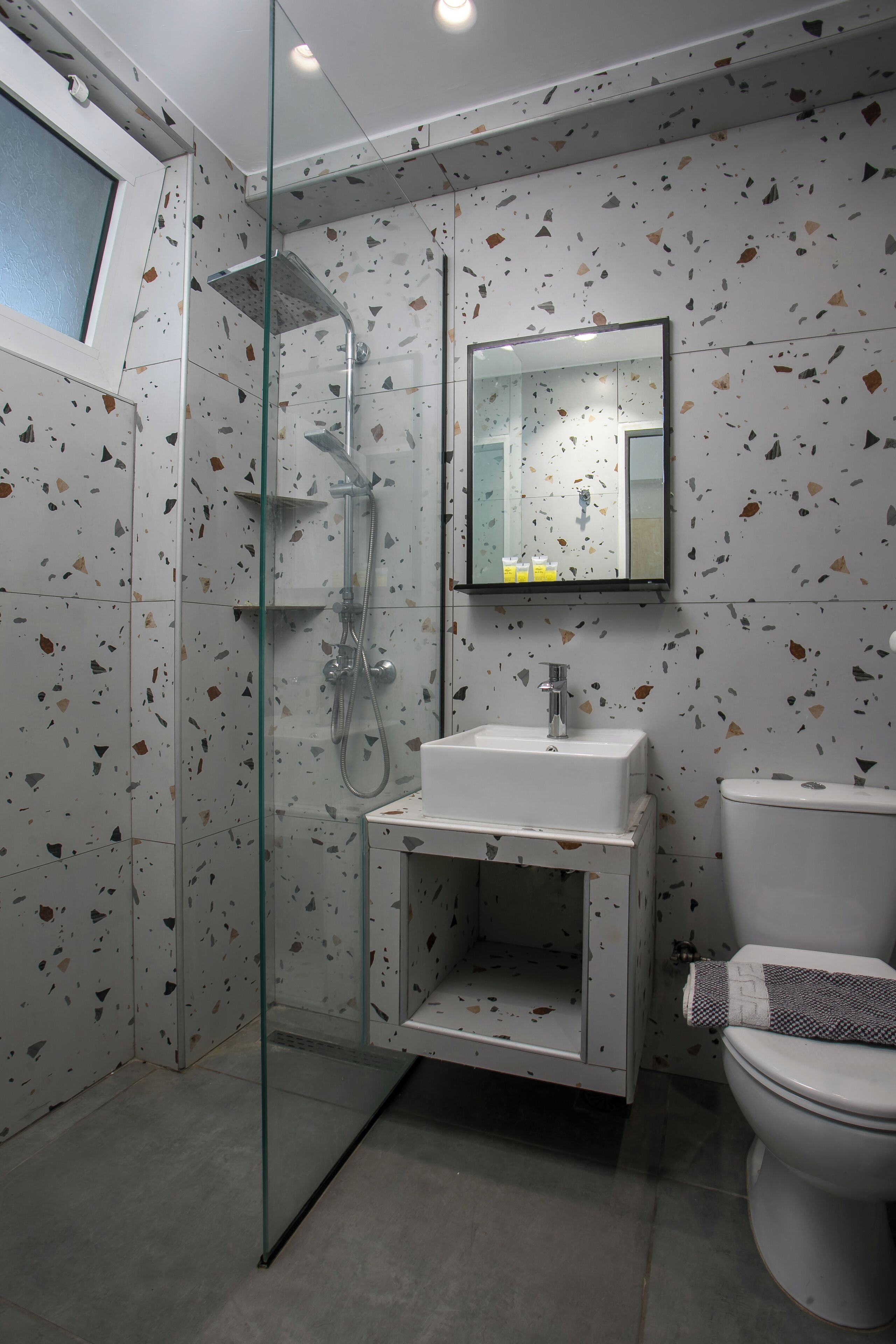 A modern bathroom with a glass shower enclosure, a white sink, and a toilet.