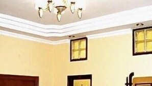 A hallway with a wooden door, a framed artwork on the wall, and a chandelier. - Stamford Residency (Bengaluru)